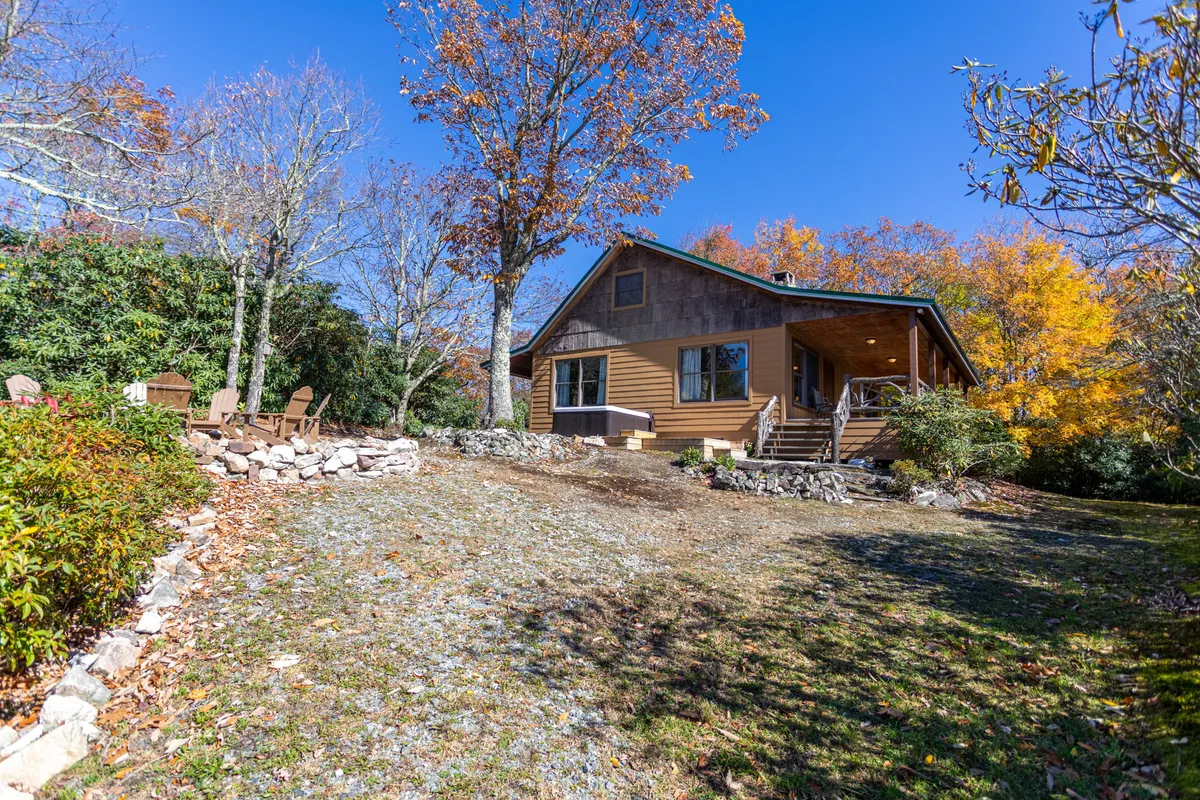 The exterior shows the house surrounded by colorful autumn trees and an inviting outdoor seating area. The natural setting suggests opportunities for family gatherings, outdoor dining, and relaxation in the embrace of nature.